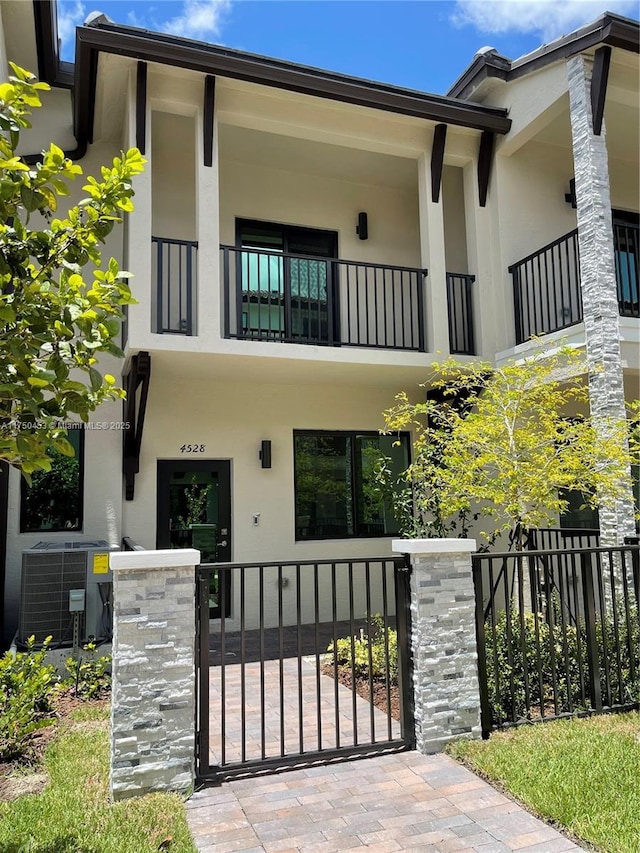 view of front of house with a fenced front yard, cooling unit, a gate, and stucco siding