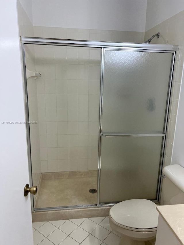 full bath with a stall shower, tile patterned flooring, vanity, and toilet