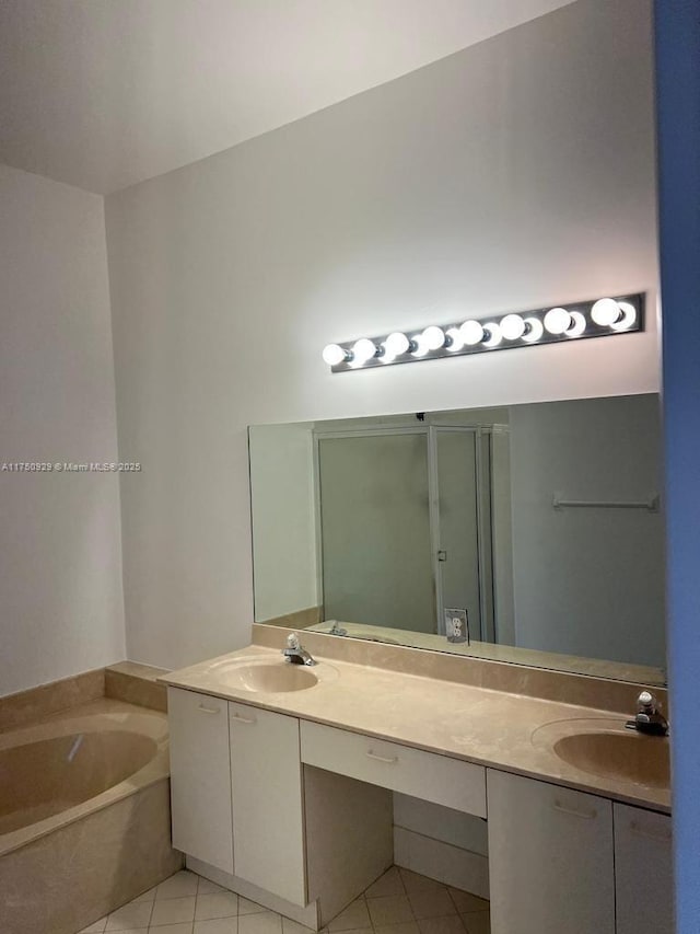 bathroom with a garden tub, double vanity, a sink, and tile patterned floors