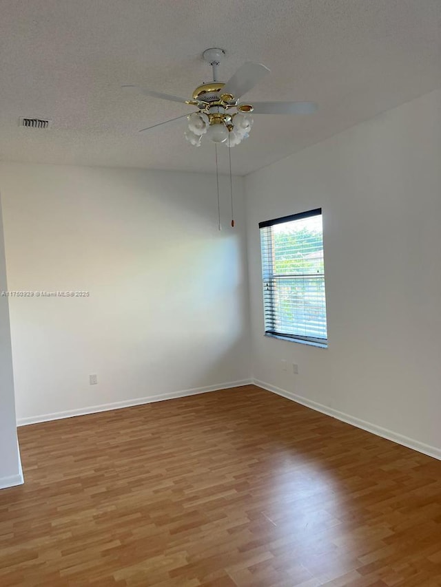 empty room with light wood-type flooring, ceiling fan, baseboards, and a textured ceiling