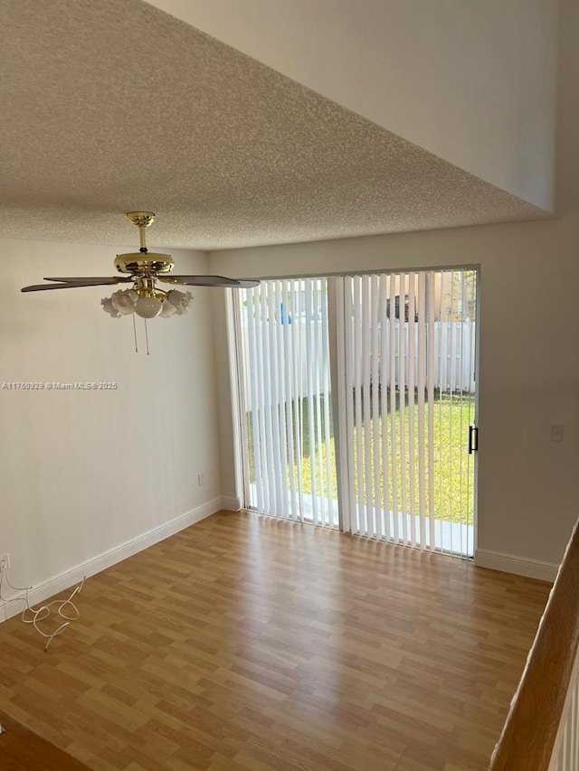 spare room with a textured ceiling, baseboards, and wood finished floors