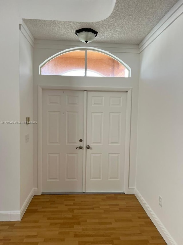 foyer with a healthy amount of sunlight, light wood-style flooring, and a textured ceiling