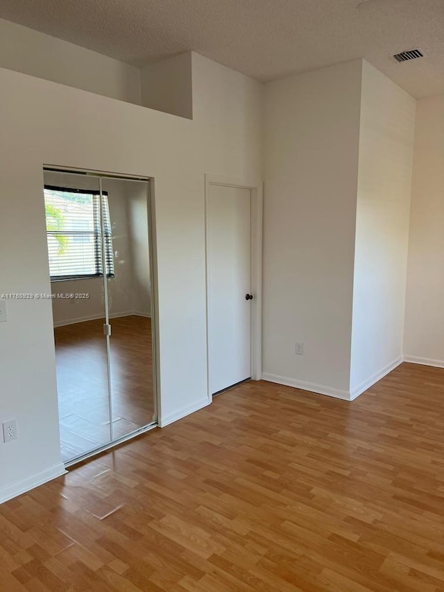 unfurnished bedroom with light wood-type flooring, baseboards, visible vents, and a textured ceiling