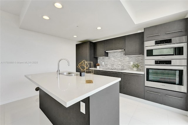 7875 NW 107th Ave Unit 518, Doral, FL 33178 - kitchen with backsplash, an island with sink, light countertops, stainless steel double oven, and a sink
