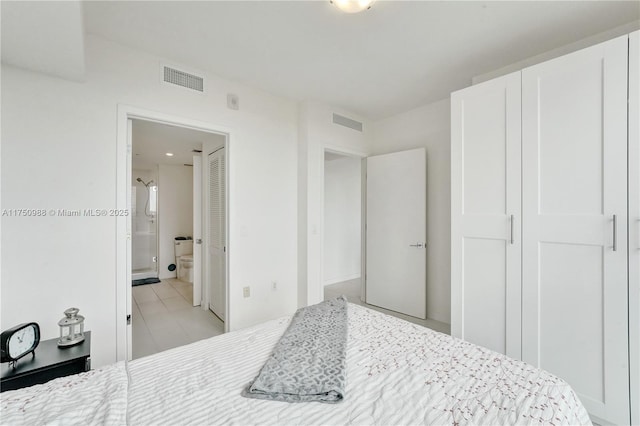 bedroom featuring light tile patterned flooring, visible vents, and ensuite bathroom