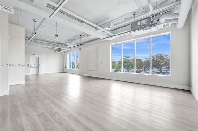 unfurnished room with baseboards, visible vents, and wood finished floors