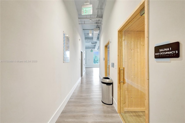 hall featuring wood walls, baseboards, and wood finished floors