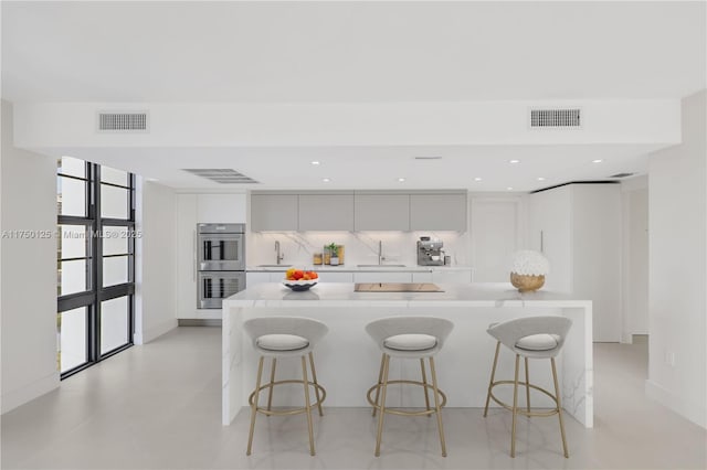 5500 Collins Ave Unit 802, Miami Beach, FL 33140 - kitchen featuring visible vents, modern cabinets, a sink, and double oven