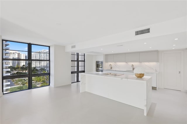 5500 Collins Ave Unit 802, Miami Beach, FL 33140 - kitchen featuring visible vents, a sink, floor to ceiling windows, and modern cabinets