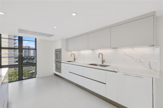 5500 Collins Ave Unit 802, Miami Beach, FL 33140 - kitchen featuring a sink, modern cabinets, and backsplash
