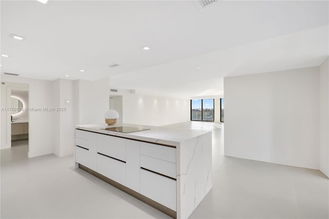 5500 Collins Ave Unit 802, Miami Beach, FL 33140 - kitchen with a center island, modern cabinets, concrete flooring, black electric cooktop, and white cabinetry