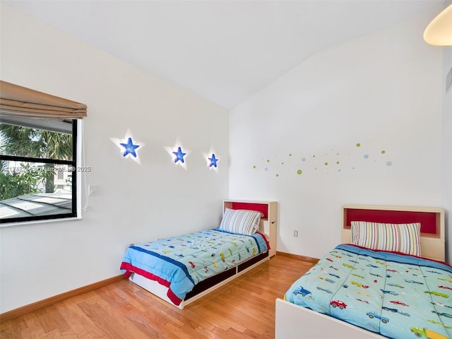 bedroom featuring lofted ceiling, wood finished floors, and baseboards