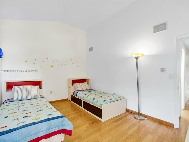 bedroom featuring vaulted ceiling, baseboards, and wood finished floors