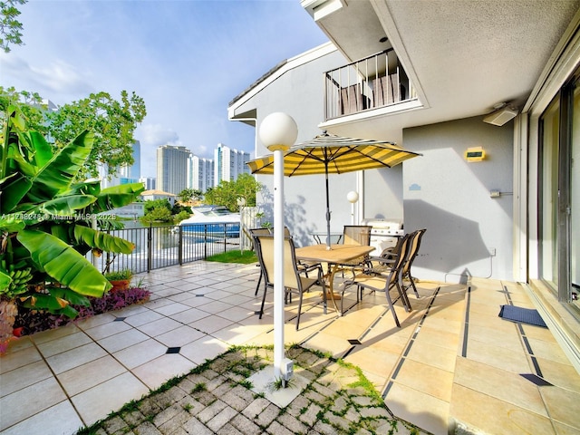 view of patio with a fenced in pool, outdoor dining area, a city view, grilling area, and fence