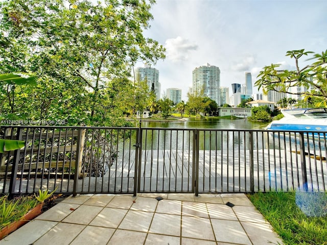 view of patio / terrace featuring a view of city, a gate, and a water view