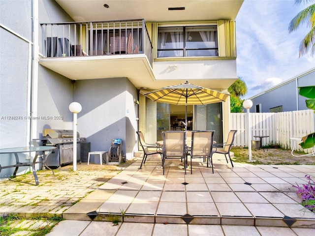 view of patio / terrace with outdoor dining area, fence, a balcony, and a grill