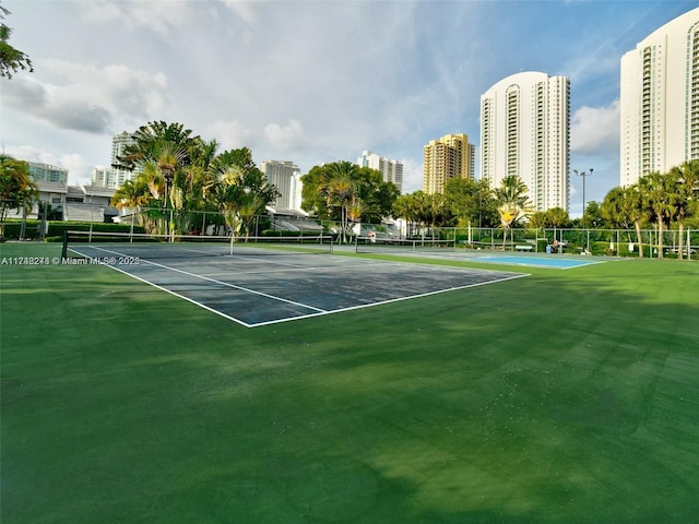 view of tennis court featuring a view of city and fence