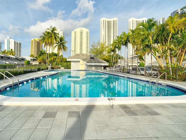 pool with a view of city, fence, and a patio