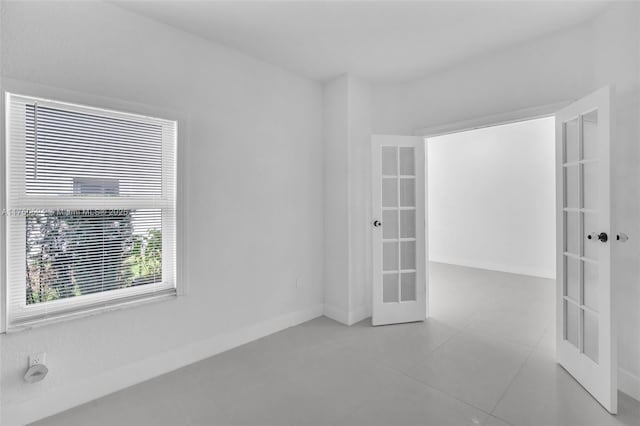 unfurnished room with light tile patterned floors, french doors, and baseboards