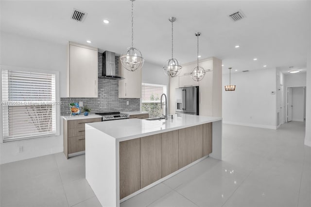 kitchen featuring a sink, visible vents, light countertops, appliances with stainless steel finishes, and wall chimney exhaust hood