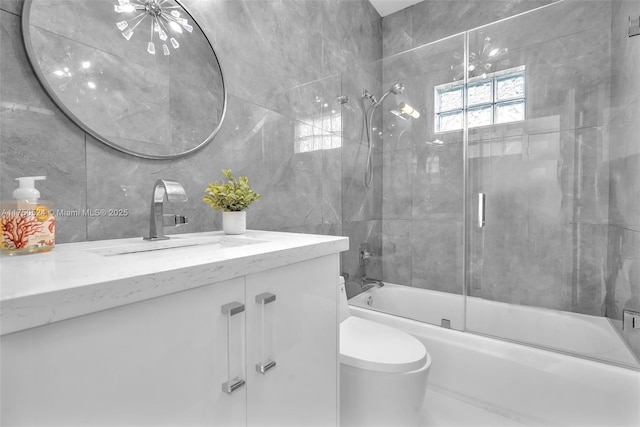 full bathroom featuring tile walls, enclosed tub / shower combo, vanity, and toilet