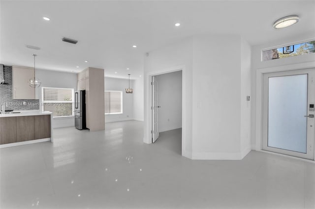 unfurnished living room featuring baseboards, a sink, visible vents, and recessed lighting