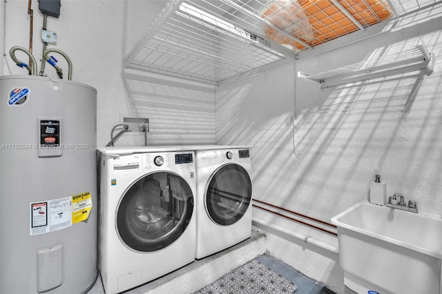 laundry area with laundry area, a sink, electric water heater, and washer and dryer