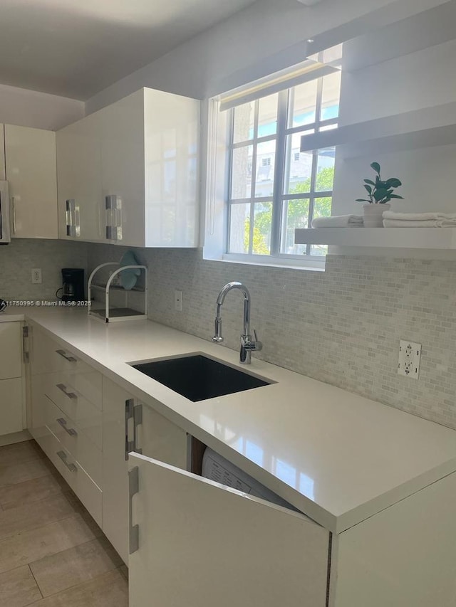 kitchen featuring a sink, white cabinetry, light countertops, decorative backsplash, and modern cabinets