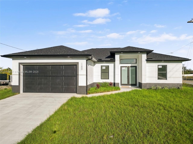 prairie-style house featuring a garage, a front lawn, concrete driveway, and stucco siding