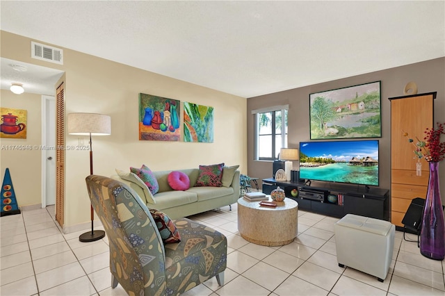 living room featuring light tile patterned floors, a textured ceiling, visible vents, and baseboards