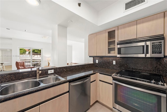 kitchen with visible vents, light brown cabinetry, appliances with stainless steel finishes, a sink, and dark stone counters