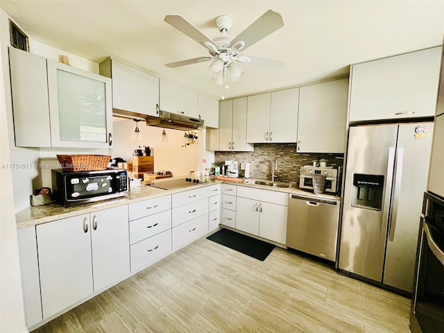 kitchen with stainless steel appliances, white cabinets, a sink, and tasteful backsplash