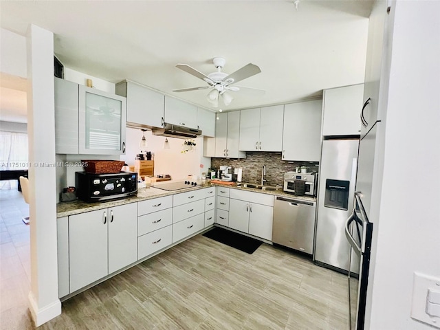 kitchen with stainless steel appliances, light countertops, decorative backsplash, white cabinets, and a sink