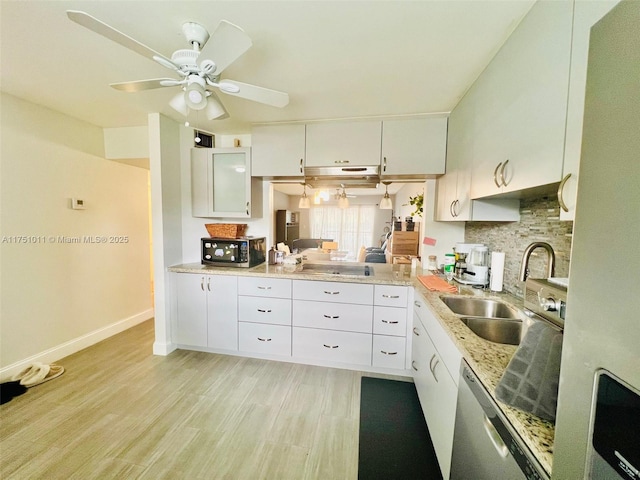 kitchen with stainless steel appliances, a sink, white cabinetry, light wood finished floors, and tasteful backsplash