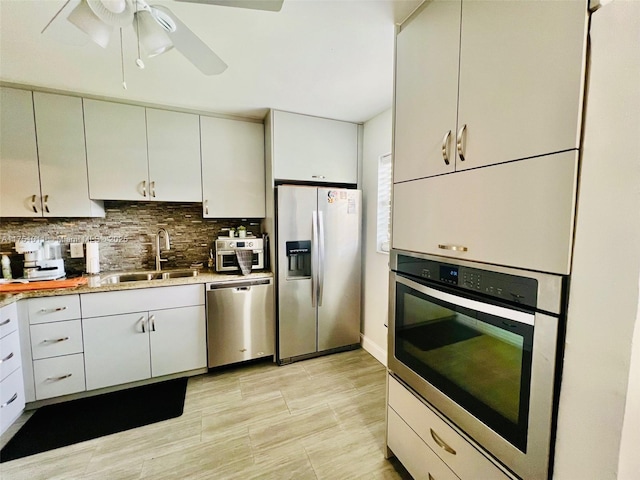 kitchen featuring light countertops, backsplash, appliances with stainless steel finishes, white cabinets, and a sink