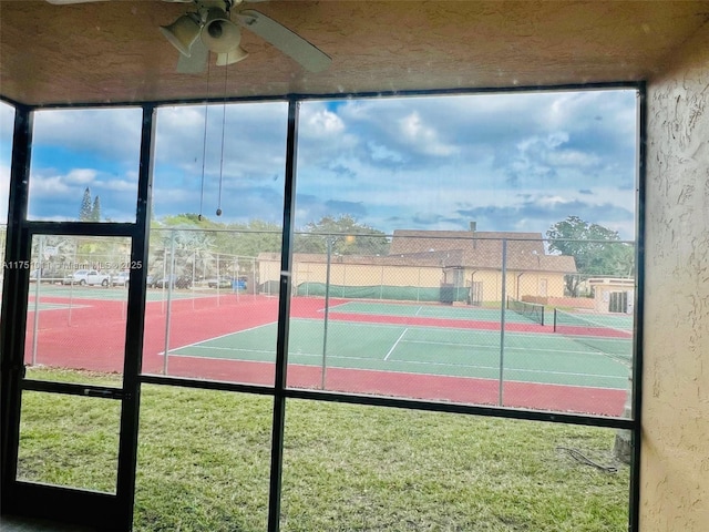 view of tennis court featuring fence and a ceiling fan