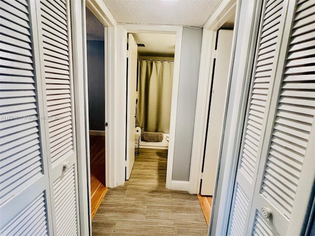 corridor featuring light wood-style flooring and a textured ceiling