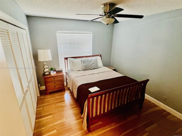 bedroom with a textured ceiling, wood finished floors, a ceiling fan, baseboards, and a closet