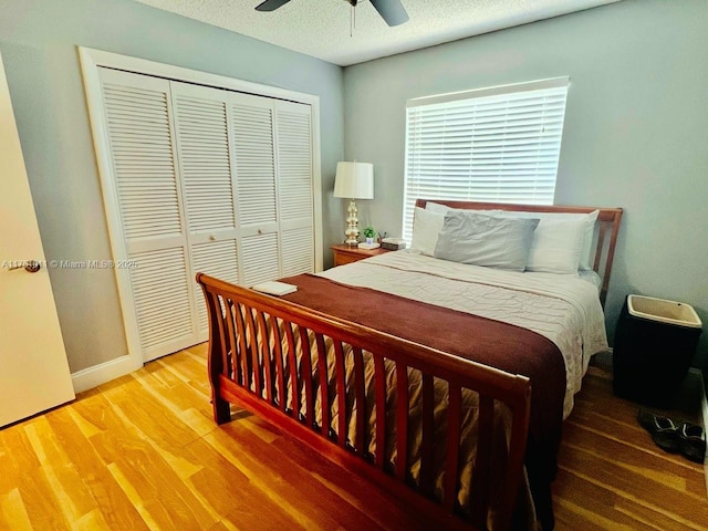 bedroom featuring a closet, ceiling fan, a textured ceiling, wood finished floors, and baseboards