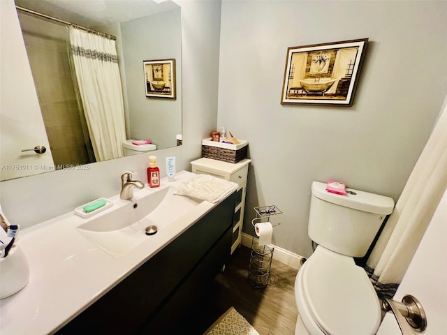 bathroom with toilet, baseboards, wood finished floors, and vanity