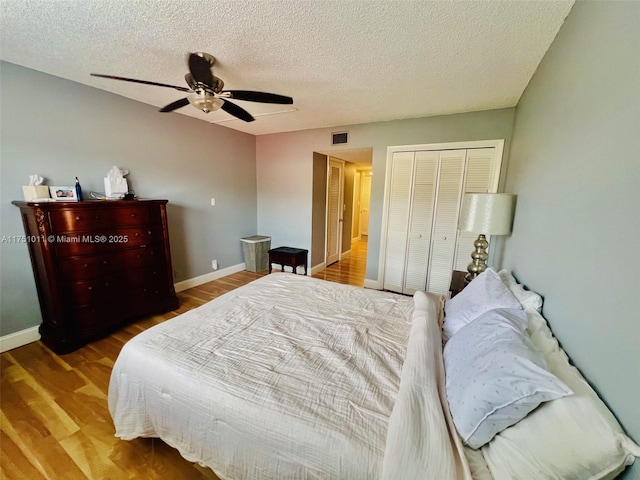 bedroom with visible vents, ceiling fan, a textured ceiling, wood finished floors, and baseboards