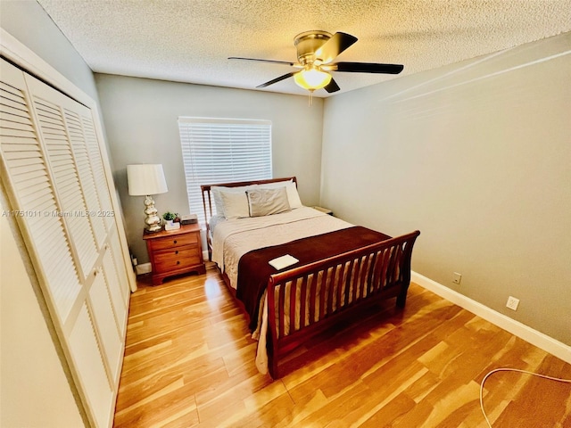 bedroom featuring baseboards, a ceiling fan, wood finished floors, a textured ceiling, and a closet