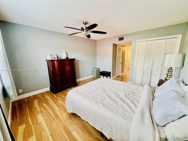 bedroom featuring baseboards, a textured ceiling, visible vents, and wood finished floors