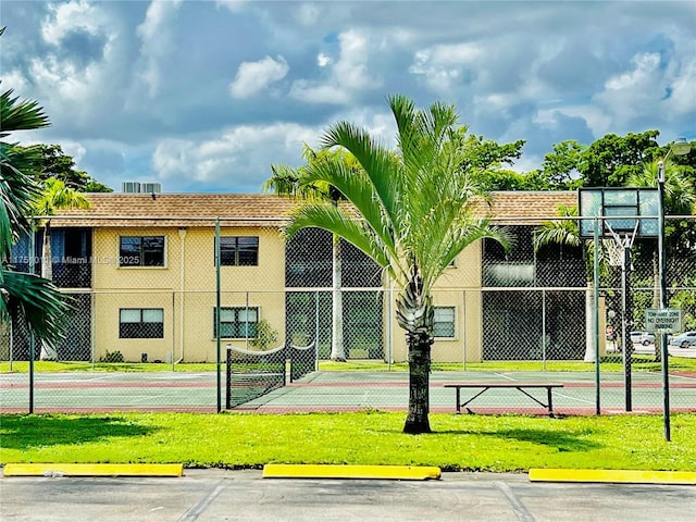 surrounding community featuring a yard, uncovered parking, community basketball court, and fence