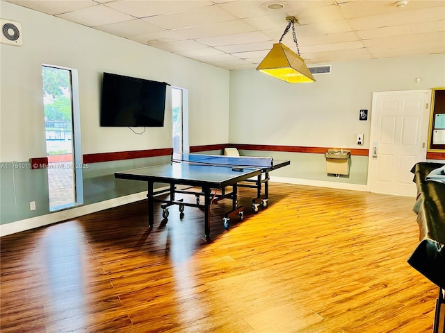 playroom featuring a paneled ceiling, visible vents, baseboards, and wood finished floors