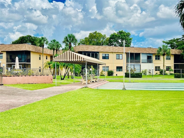 view of community with a lawn and shuffleboard