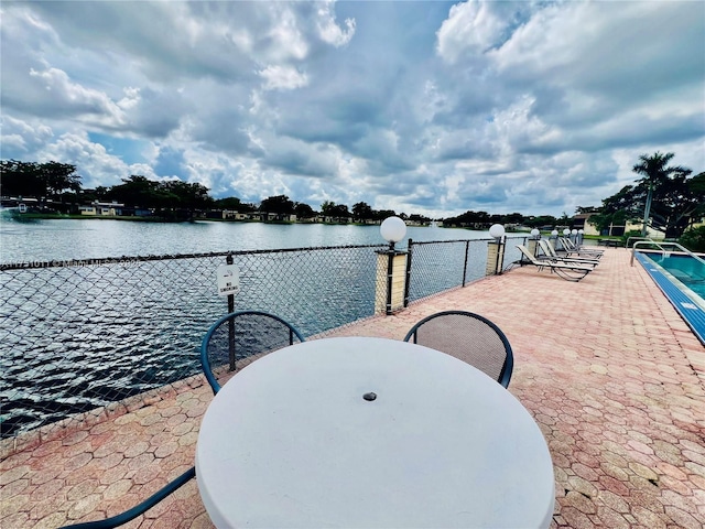 view of patio with a water view and fence