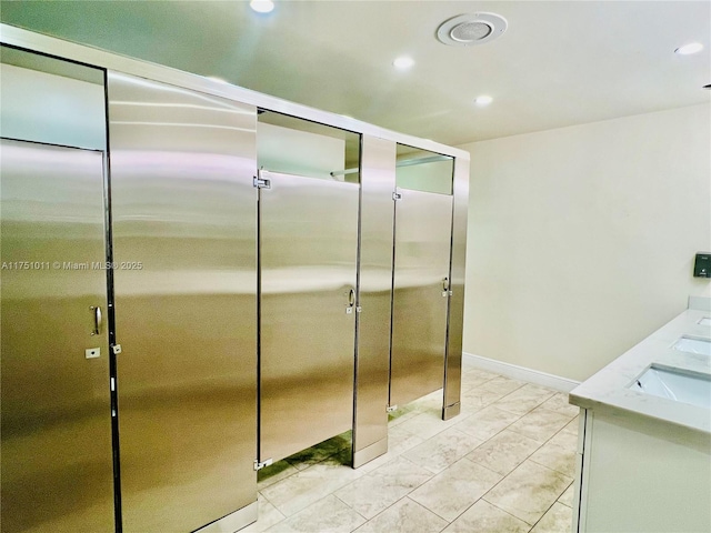 kitchen featuring light stone countertops, baseboards, a sink, and recessed lighting