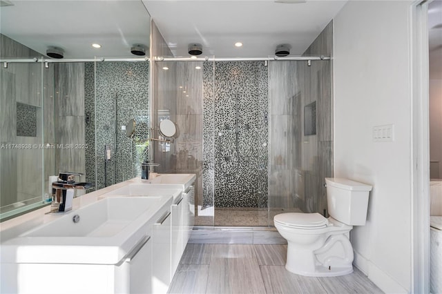 bathroom featuring recessed lighting, a sink, toilet, and a shower stall