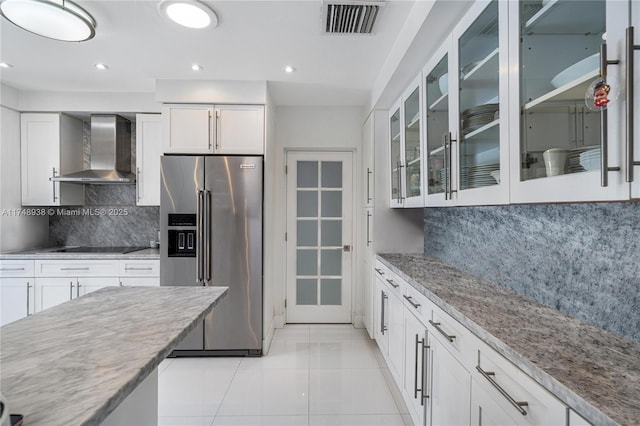 kitchen with glass insert cabinets, white cabinetry, high quality fridge, and wall chimney range hood